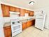 Modern kitchen with sleek granite countertops, wooden cabinets, and appliances including stove and refrigerator.