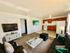 Inviting living space with plush seating, modern d&eacute;cor, and an elegant open kitchen featuring rich wood cabinets and bright lighting.