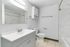 Bright and modern bathroom featuring a chic marble-tiled shower, elegant vanity with a sleek mirror, and contemporary fixtures.