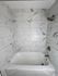 Elegant bathroom showcasing luxurious marble tile walls and a modern bathtub with a sleek showerhead.