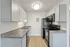 Modern kitchen with sleek black appliances, elegant gray cabinetry, and stylish granite countertops, exuding contemporary charm.