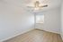 Bright and airy room with modern ceiling fan and large window, featuring sleek laminate flooring and fresh white walls.