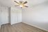 Bright and airy room with modern fan, sleek wooden flooring, and ample storage with white closet doors.