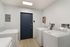 Modern laundry room with two sleek, white washing machines, bright lighting, and a stylish dark door.