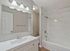 Elegant bathroom with modern vanity, well-lit mirror, and luxurious marble-tiled bathtub.