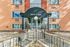 Charming apartment entrance with classic brick facade and modern awning, featuring well-maintained landscaping and inviting walkways.