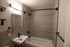 Modern bathroom featuring a sleek tile design, elegant fixtures, and a spacious bathtub with a stylish curved shower rod.