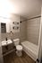 Modern bathroom featuring elegant tiled walls, sleek fixtures, and a cozy bathtub, perfect for relaxation.