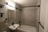Modern bathroom with sleek gray tile, elegant fixtures, and a spacious bathtub.