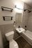 Modern bathroom featuring sleek fixtures, elegant grey tiles, and contemporary shelving.