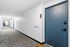 Contemporary apartment corridor with stylish blue doors and carpet, offering a welcoming entrance to modern living spaces.