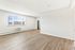 Bright and airy living space with large window, sleek hardwood floors, and modern kitchen entryway.