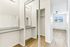 Elegant apartment interior featuring a spacious walk-in closet, stylish mirrored doors, and sleek wooden flooring leading to a bright, airy room with large windows and modern ceiling fan.