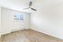 Bright, spacious room with elegant wood flooring, large window for natural light, and modern ceiling fan.