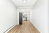 Sleek narrow kitchen with modern stainless steel appliances and elegant light wood flooring.