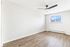Bright empty room with elegant wooden flooring, large window with soothing views, and modern ceiling fan, offering a refreshing and versatile space.
