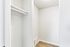 Bright and spacious walk-in closet with sleek white walls and hardwood flooring, perfect for ample storage.