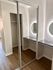 Modern apartment interior featuring a spacious walk-in closet with sliding mirrored doors and a stylish vanity area with illuminated round mirrors.