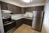 Modern kitchen with stainless steel appliances, elegant dark wood cabinets, and sleek granite countertops.