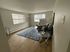 Bright and welcoming living room with modern furniture, large windows, and sleek wood flooring.