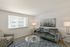Bright and welcoming living room featuring stylish gray sofa, modern artwork, and elegant glass coffee table.