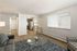 Contemporary living room with cozy seating, stylish glass coffee table, and natural light streaming through large windows. Open view into a sleek kitchen with stainless steel appliances.