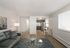 Modern open-concept living room with chic grey sofa, elegant glass coffee table, and cozy dining area next to a sleek kitchen featuring stainless steel appliances.
