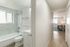Inviting hallway leading to a cozy living space filled with natural light, adjacent to a modern bathroom featuring elegant marble tiles.