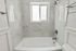 Elegant bathroom with modern marble tiles, a spacious bathtub, and a large window for natural light.