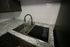 Modern kitchen sink with elegant marble countertop and stylish wave-patterned backsplash.