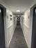 Inviting apartment hallway with modern art decorations and elegant wainscoting, leading to stylishly numbered doors.