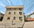 Charming three-story apartment building with unique textured facade and ample windows, located in a serene neighborhood, offering comfortable living spaces.