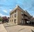 Charming apartment building with textured exterior, featuring outdoor staircases and scenic landscaping under a bright sky.