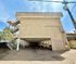 Charming urban apartment complex with stylish external staircase and ample parking under a bright blue sky.