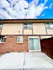 Charming brick townhouse exterior with modern sliding glass door and bright blue sky.
