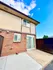 Inviting patio area with clean brick exterior and sliding glass door, perfect for outdoor relaxation under a clear blue sky.