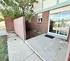 Charming apartment patio with sliding glass doors, brick exterior, and a private fenced area enhanced by lush greenery.
