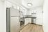 Modern kitchen with sleek stainless steel appliances, bright white cabinetry, and elegant wood flooring.