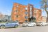 Charming red brick apartment building with modern design, featuring large windows and a welcoming entrance, set in a vibrant neighborhood.