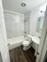 Elegant bathroom featuring a modern design with marble-style tiles, a cozy bathtub, and sleek fixtures.