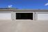 Spacious double garage with modern white doors and ample driveway space under clear blue skies.