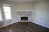 Contemporary living room with elegant stone fireplace, large windows, and modern flooring.