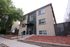 Modern brick apartment building with landscaped entrance and large windows, offering stylish urban living.