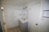 Bright and modern bathroom with a sleek vanity, large mirror, and neutral tiles, featuring a spacious closet for convenient storage.