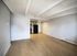 Spacious open-concept living area with modern kitchen, featuring sleek cabinets and warm wooden flooring.