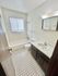 Bright bathroom featuring elegant white tiles, a classic bathtub, and a sleek vanity with ample storage.