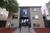 Charming apartment building featuring a modern entrance with large windows, surrounded by manicured landscaping and stylish brickwork.