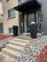 Charming apartment entrance with modern design, featuring sleek planters and a welcoming pathway surrounded by decorative stones.