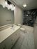 Elegant bathroom featuring a sleek marble-tiled shower, modern vanity with ample storage, and contemporary lighting.