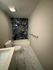 Elegant bathroom featuring modern fixtures, luxurious marble tile accent wall, and sleek tile flooring.